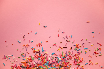 Colorful sprinkles scattered on pink background