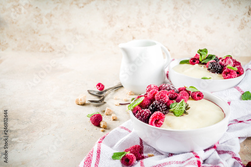 Two bowl with Semolina porridge with fresh berries, beige stone table copy space top view photo