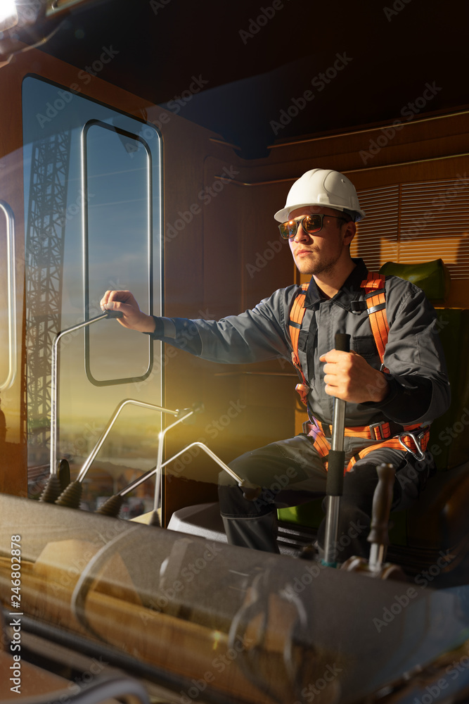 Engineer operator crane in action . He sit a top in crane cabin and working. Around beautiful sunset Engineer operator crane in action . He sit a top in crane cabin and working. Around beautiful sunset