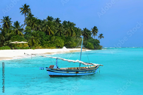 Paradise maldivian landscape with a traditional wooden sailboat, palm trees and the turquoise sea. Maldive islands (Maldives). 