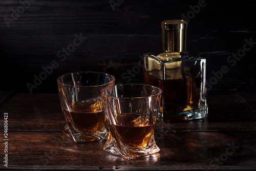 bottle and glasses of whisky on brown wooden table