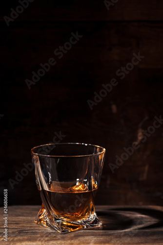close-up view of whiskey in glass and reflection on wooden table