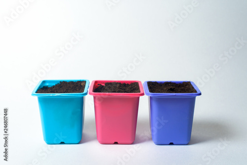plastic containers for planting seeds on seedlings. pots of different colors on white background. isolable © Taranova_ksenya
