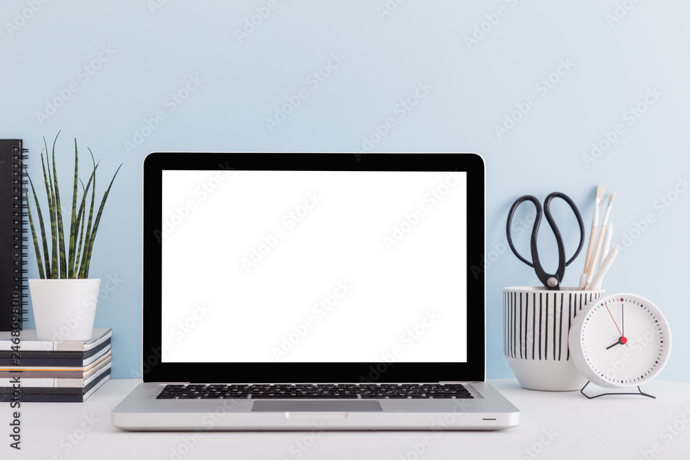 Fototapeta premium Laptop at blue wall background home office workspace. Mock up. 