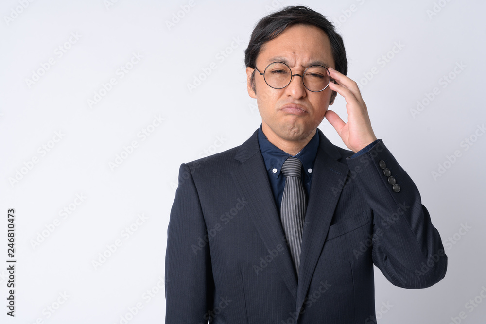 Portrait of stressed Japanese businessman in suit having headache Portrait of stressed Japanese businessman in suit having headache