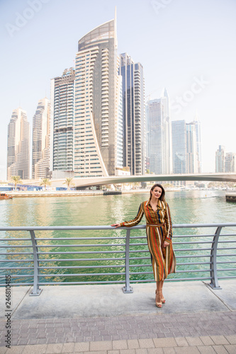 Beautiful woman portrait enjoying the view of skyscrapers at Dubai Mall with fountains in the background. © dianagrytsku