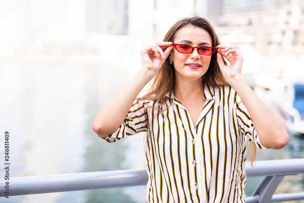 Young beautiful woman tourist woman in fashionable sunglasses enjoying in Dubai marina in United Arab Emirates.