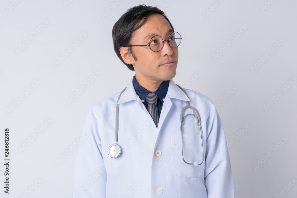 Portrait of Japanese man doctor thinking and looking up Portrait of Japanese man doctor thinking and looking up