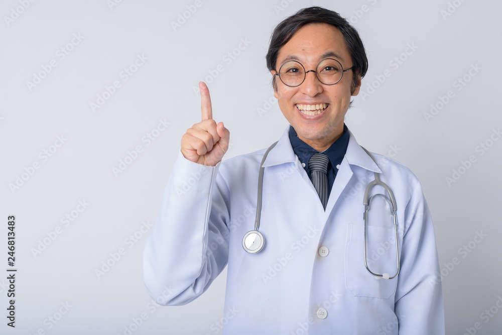Portrait of happy Japanese man doctor pointing up Portrait of happy Japanese man doctor pointing up