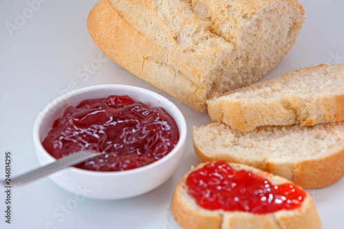  White bread and strawberry jam on a white background.