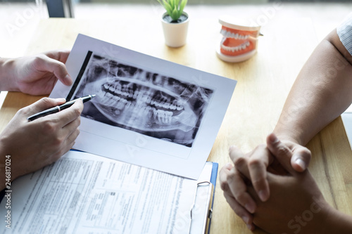 Image of doctor or dentist presenting with tooth x-ray film recommend patient in the treatment of dental and dentistry, working at workplace