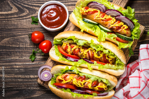 Hot dog with fresh vegetables on wooden table.