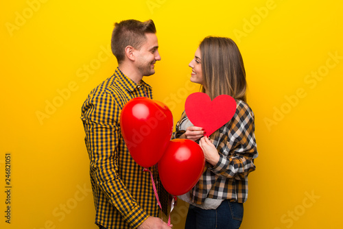 Couple in valentine day holding a heart symbol and balloons