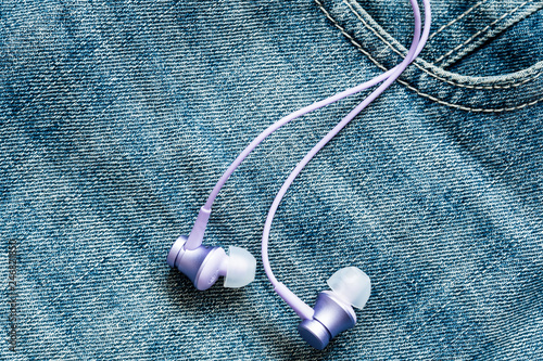 Earphones on the surface of blue jeans