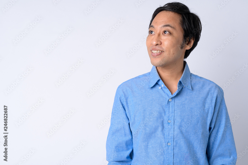 Portrait of happy Japanese businessman thinking against white background Portrait of happy Japanese businessman thinking against white background