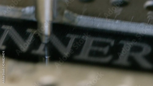 Camera pans across a CNC engraver shading text of the word WINNER