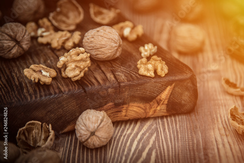 Close up view composition of walnut kernels and whole walnuts on rustic cuting desk. Selective focus. toned