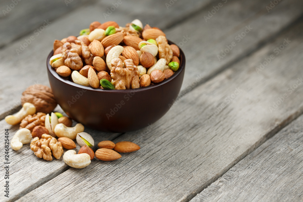 Wooden bowl with mixed nuts on a wooden gray background. Walnut, pistachios, almonds, hazelnuts and cashews, walnut. Wooden bowl with mixed nuts on a wooden gray background. Walnut, pistachios, almonds, hazelnuts and cashews, walnut.