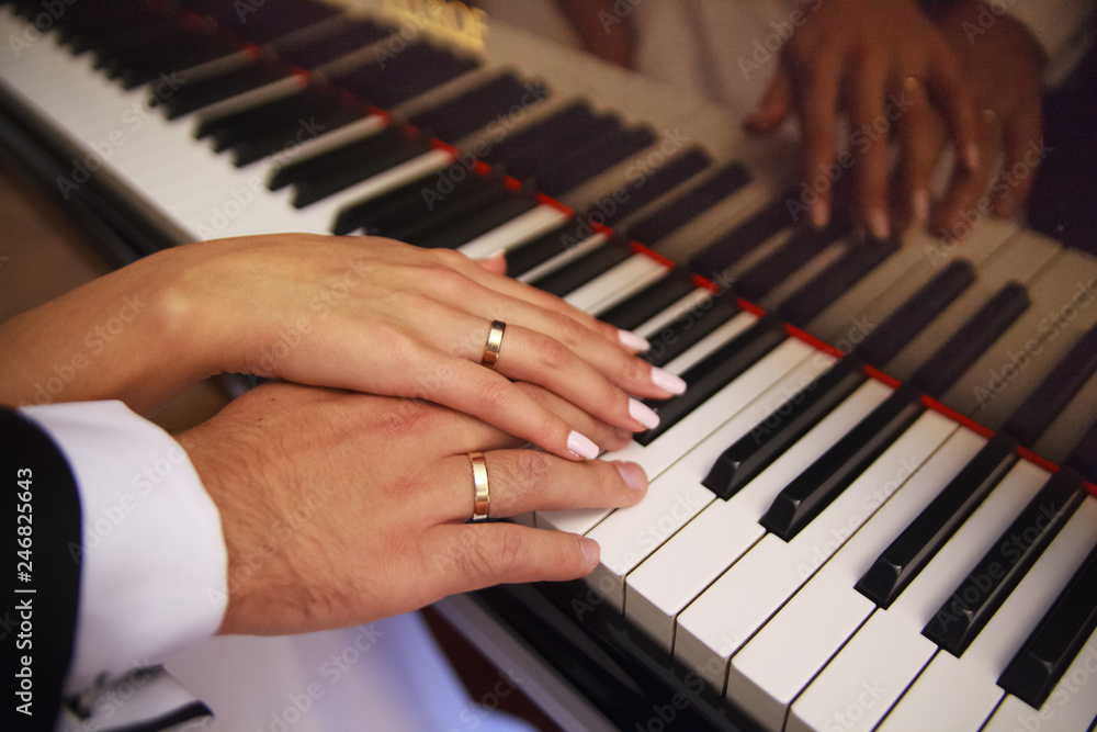 Two hands on the piano. Play. The piano keys. Wedding. A touch of hands. Wedding rings. Closeup