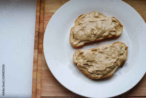 Delicious peanut butter sandwich breakfast on white plate, wooden table background. Sweet food, breakfast concept