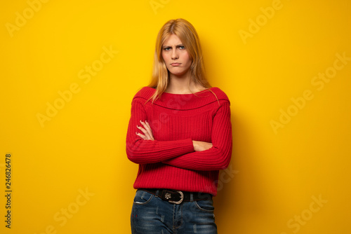 Blonde woman over yellow wall feeling upset