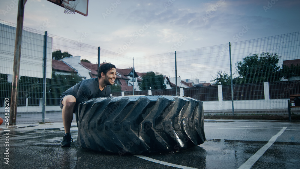 Φωτογραφία Strong Muscular Fit Young Man in Sport Outfit and Gloves is Doing Exercises in a Fenced Outdoor Basketball Court