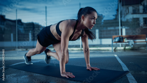 Beautiful Energetic Fitness Girl Doing Mountain Climber Exercises. She is Doing a Workout in a Fenced Outdoor Basketball Court. Evening Shot After Rain in a Residential Neighborhood Area.