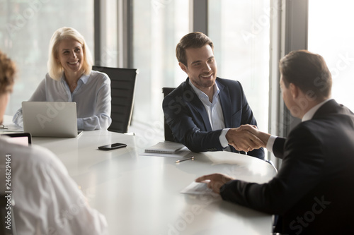 Happy business partners shaking hands expressing respect, closing banking investment corporate deal, welcoming at office group meeting, handshake of smiling businessmen as collaboration concept