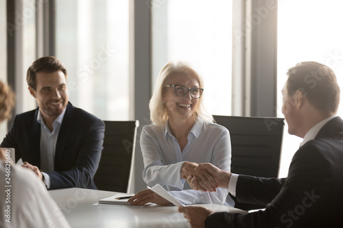 Fotografie Happy mature businesswoman handshaking new male partner, ceo and smiling middle