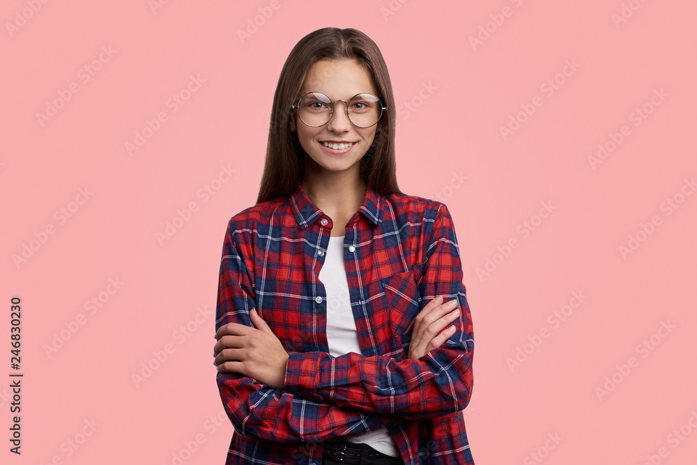 Glad female model crosses hands over chest, isolated over pink background. People, youth, emotions concept Glad female model crosses hands over chest, isolated over pink background. People, youth, emotions concept
