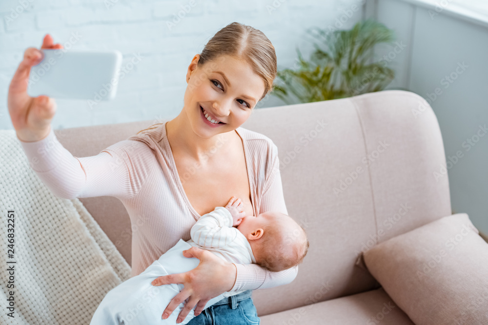 happy young woman breastfeeding baby and taking selfie with smartphone at home happy young woman breastfeeding baby and taking selfie with smartphone at home