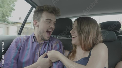 Naughty girlfriend twisting boyfriend nipple making joke and laughing while standing in the backseat of taxi car hanging out photo