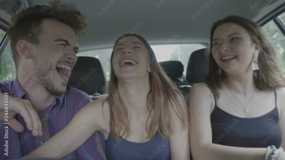 Happy crazy friends dancing and laughing in the back of driving taxi car while they hanging out Happy crazy friends dancing and laughing in the back of driving taxi car while they hanging out