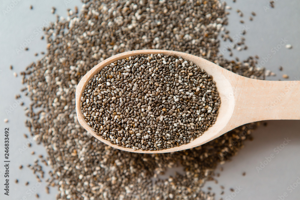 Chia seeds in wooden spoon on grey background.copy spase.Chia seeds in wooden spoon, lying on dark stone background Chia seeds in wooden spoon on grey background.copy spase.Chia seeds in wooden spoon, lying on dark stone background