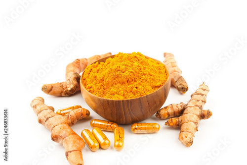 Turmeric capsules and turmeric powder in wooden bowl on white background. Herbal photo