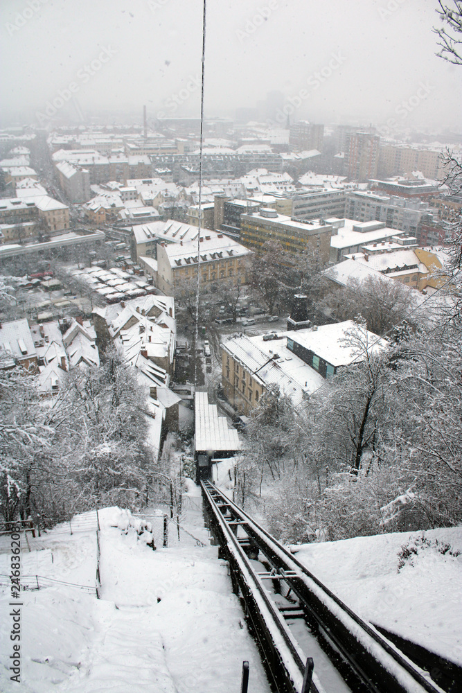 Naklejka premium Binario e cavo funicolare con nevicata urbana