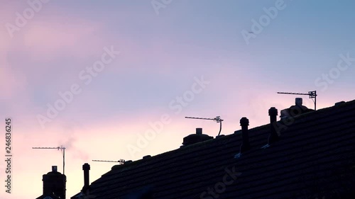 Roof tops of a residential estate shot on a cold evening. steam and smoke are emitted from the the chimneys as families try to keep themselves warm inside.
