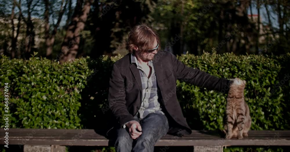 A man in the park stroking a cat A man in the park stroking a cat