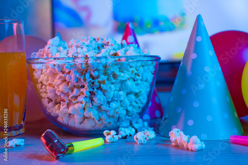 Popcorn birthday, party. On the background of TV and color bright light. Concept of festivals