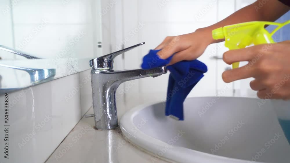 Closeup of woman hand cleaning bathroom faucet with a cloth and spray. Shot in 4k resolution Closeup of woman hand cleaning bathroom faucet with a cloth and spray. Shot in 4k resolution
