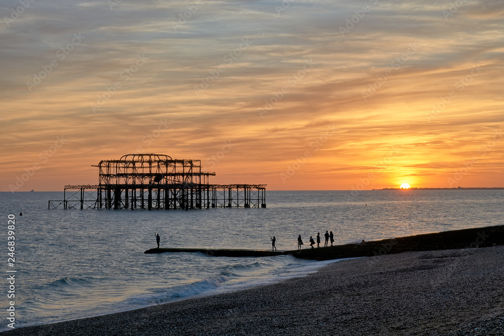 The ruins of Brighton's West pier silhouetted against a setting sun.