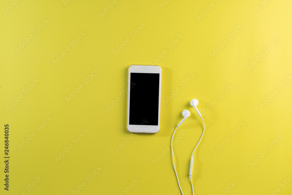 Top view cell phone and earphone on white desk Top view cell phone and earphone on white desk