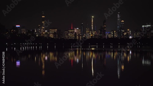 Manhattan Urban Cityscape and Reflection in Jacqueline Kennedy Onassis Reservoir in Central Park at Night. New York City. United States of America. Panning Shot