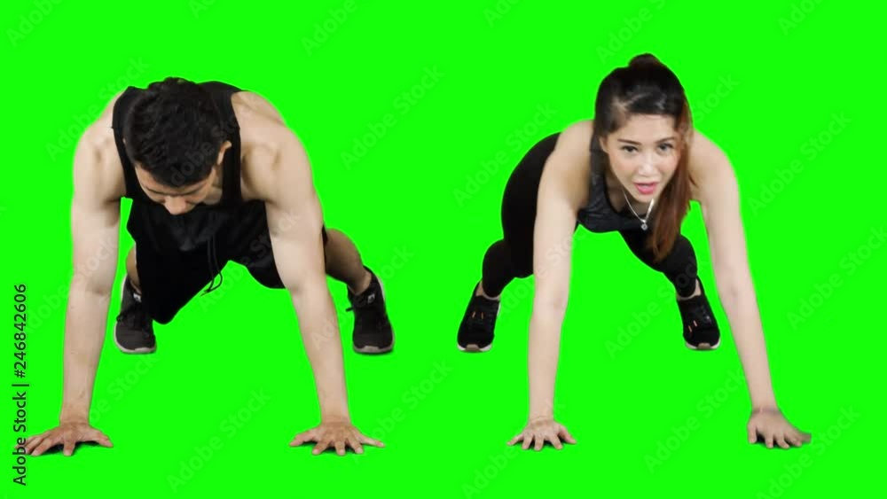 Attractive young couple doing plank exercise and making high five together. Shot in 4k resolution with green screen background Attractive young couple doing plank exercise and making high five together. Shot in 4k resolution with green screen background