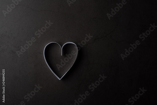 White heart shaped paper in shadow on black background