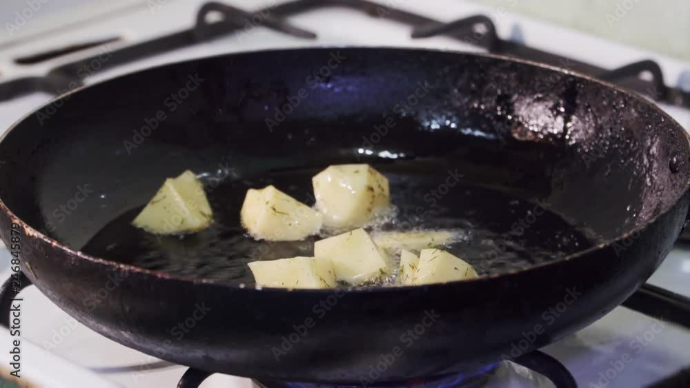 Peeled potatoes are thrown into a frying pan with hot vegetable oil Peeled potatoes are thrown into a frying pan with hot vegetable oil