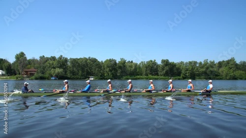 Rowing team summer training. 8 athletes rowers in a boat in the river Dnipro. City area in Kiev, Ukraine