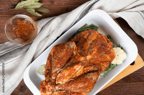 Raw guinea fowl smeared with spices with paprika lies on a white dish for baking with garlic and rosemary