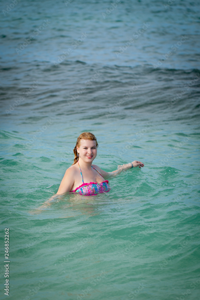 Young blonde woman in bikini in a sea bathing