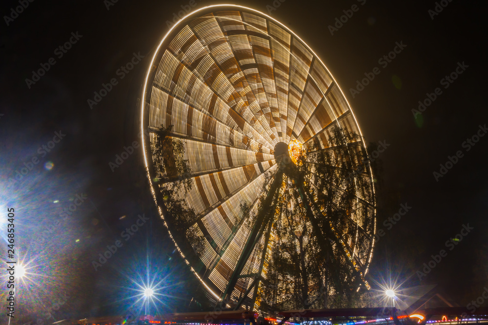 Ferris wheel in motion at the amusement park, night illumination. Long exposure